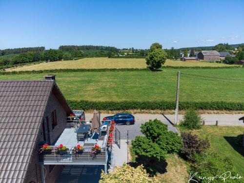 uma vista aérea de uma casa com flores e um parque de estacionamento em Le toit des Fagnes em Jalhay