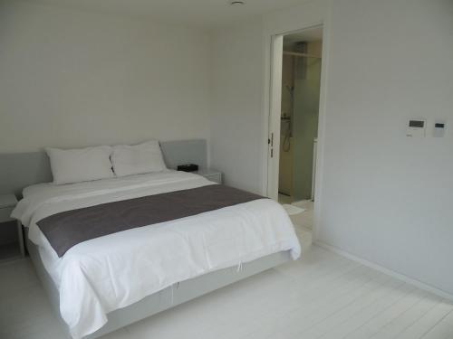a white bedroom with a large bed and a doorway at Healthcare Town Resort in Seogwipo