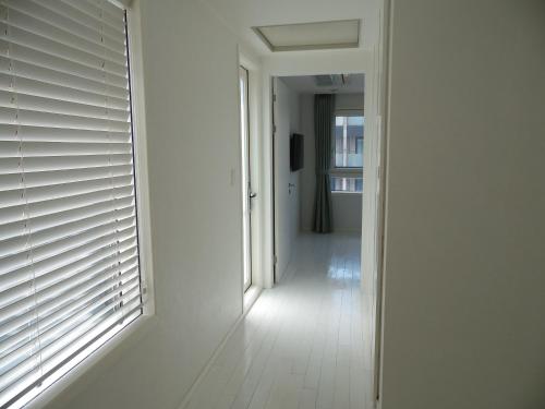 a hallway with white walls and a window with blinds at Healthcare Town Resort in Seogwipo