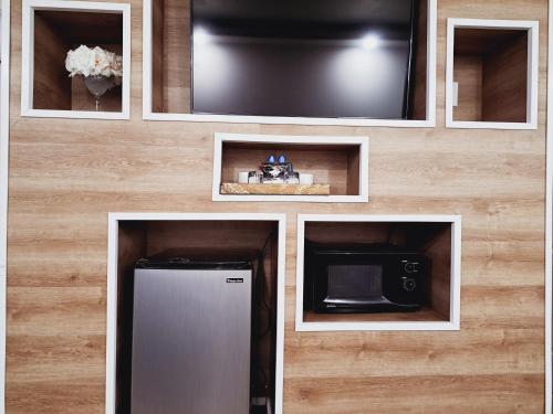 a wall with a tv and a refrigerator and a microwave at Dunes Motel - Bend in Bend
