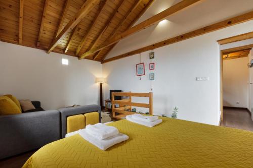 a bedroom with a yellow bed and a couch at Casas da Pedreira in Lajes do Pico