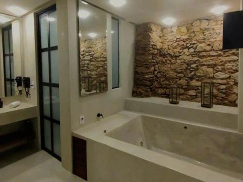 La salle de bains est pourvue d'une grande baignoire et d'un mur en pierre. dans l'établissement Casa Oyá, à Morro de São Paulo