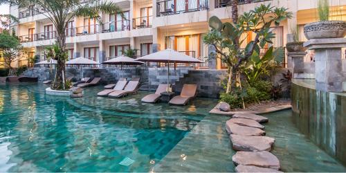 a swimming pool with chairs and umbrellas in a hotel at Anumana Ubud Hotel in Ubud