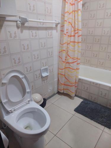 y baño con aseo y cortina de ducha. en Departamento Temporal Pardo, en Lima