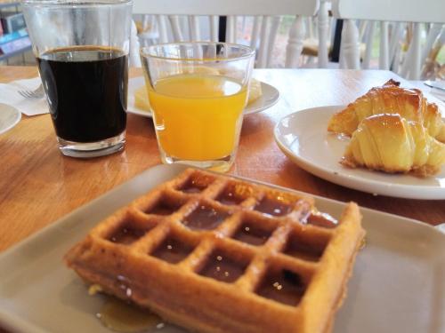 a table with a plate of waffles and a glass of orange juice at La Bonita Suites Punta Colorada in Punta Colorada