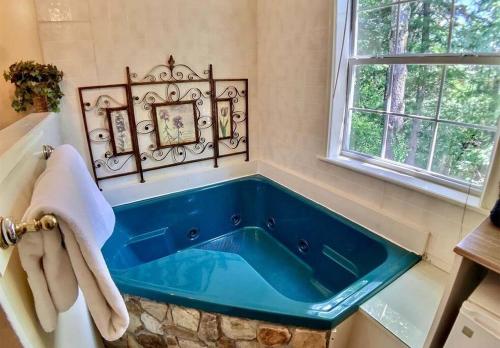 eine blaue Badewanne im Bad mit Fenster in der Unterkunft Tuscany Dream Rock Cottage/#8 in Eureka Springs