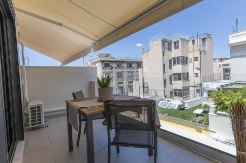 a balcony with a table and chairs and a large window at Aethir Urban Stay by Raise in Athens