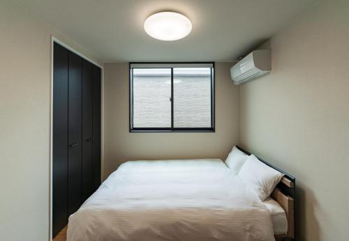 a small bedroom with a bed and a window at Flower Base Fuji in Muromimachi