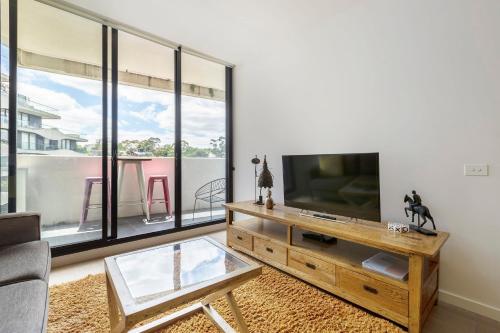 a living room with a flat screen tv and a table at Abbotsford Short Stay Luxury Style & Location in Melbourne