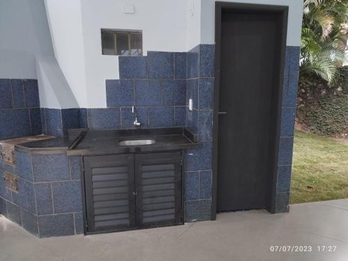 a blue tiled wall with a sink in a house at Quarto e piscina in Marechal Cândido Rondon