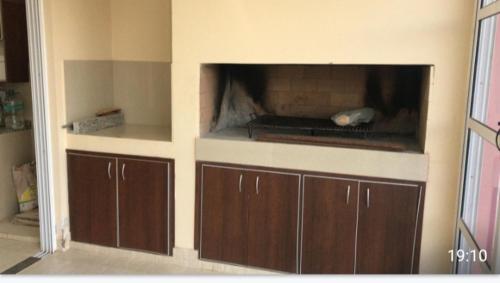 a kitchen with brown cabinets and a fireplace in the wall at Refugio de los llanos in Chamical