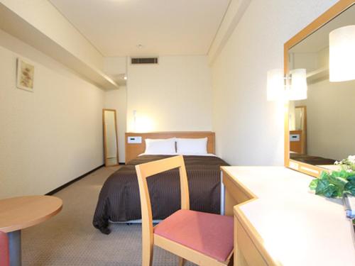a hotel room with a bed and a table at HOTEL LiVEMAX BUDGET Yokohama Kannai in Yokohama