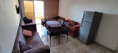 uma sala de estar com uma mesa e um frigorífico em شاليه 1 ها اول علوى ٣غرف عائلات ترى البحر والبحيرة em El Alamein