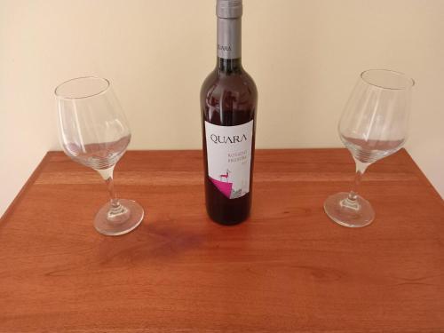 a bottle of wine and two glasses on a wooden table at El Tonel in Cafayate