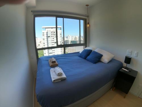 a bedroom with a blue bed with towels on it at Aconchegante Apartamento Itaim B- Vila Nova in Sao Paulo