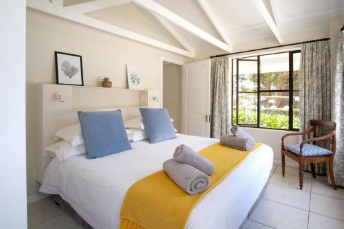 1 dormitorio con 1 cama blanca grande con almohadas azules en High Season Farm Luxury Cottages, en Hermanus