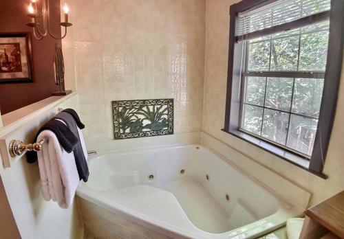 baño con bañera blanca y ventana en D'vinery Rock Cottage/ #6 en Eureka Springs