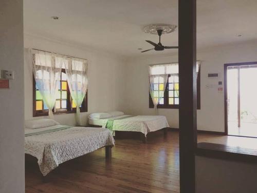 a room with two beds and a ceiling fan at MILLBROOK HOUSE TERENGGANU in Kampong Pasir Puteh