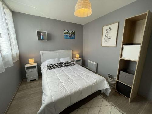 - une chambre avec un lit blanc et 2 tables de chevet dans l'établissement Appartement rénové 2 pièces, balcon, parking privé, à 200m de la plage, 4 couchages - Saint-Hilaire-de-Riez - FR-1-224C-269, à Saint-Hilaire-de-Riez