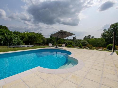 une piscine avec un parasol et un patio dans l'établissement Maison Authentique avec Piscine, Étang Privatif et Confort Moderne en Dordogne - FR-1-616-332, à Agonac