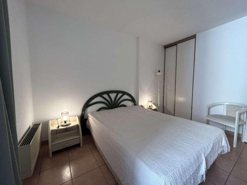 une chambre avec un lit blanc et une chaise dans l'établissement Appartement lumineux avec terrasse, parking et proche plage à Sainte-Maxime - FR-1-226-527, à Sainte-Maxime