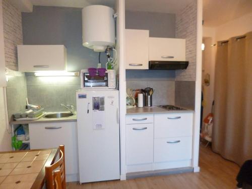 une cuisine avec un réfrigérateur blanc et une table dans l'établissement Studio 1 étoile proche du parc et de l'établissement Thermal, équipé pour 2 personnes - FR-1-571-58, à Balaruc-les-Bains