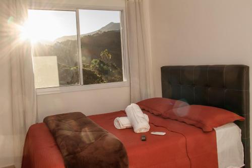 1 dormitorio con cama y ventana con vistas en Apartamento inteiro, de frente para mercado REDE ECONOMIA, com vista para montanhas, en Petrópolis