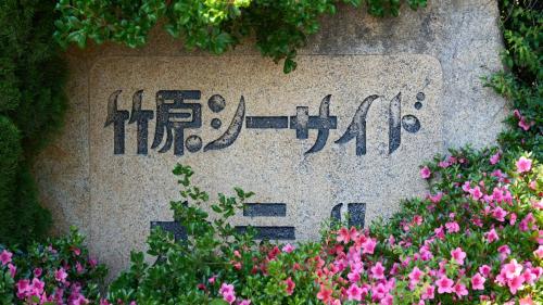 Takekara的住宿－Tabist Setouchinoyado Takehara Seaside，花中间的一个石牌