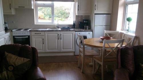 a kitchen with a table and a sink and a refrigerator at Villa Pio Luxury Apartment 3km from historic Cong, Ashford Castle, Ashford Lodge in Cong