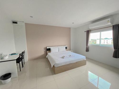 a bedroom with a bed and a desk and a window at SC Residences in Surat Thani