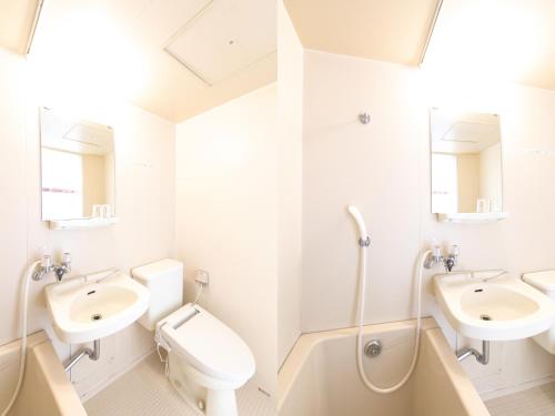 a white bathroom with two sinks and a toilet at Tabist Setouchinoyado Takehara Seaside in Takekara