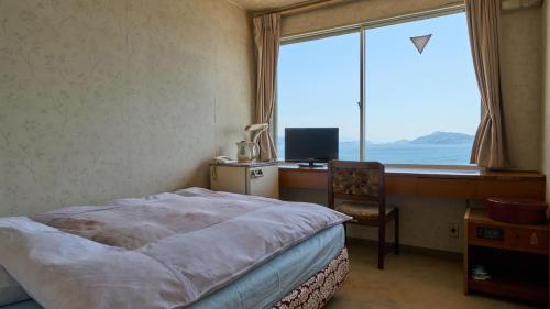 a bedroom with a bed and a desk and a window at Tabist Setouchinoyado Takehara Seaside in Takekara