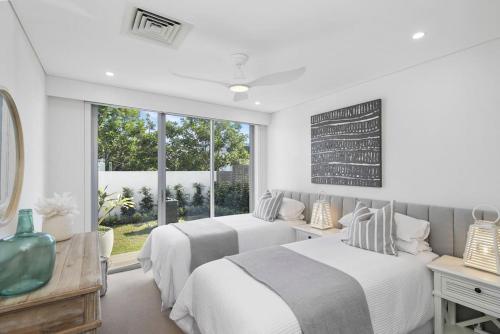 um quarto branco com 2 camas e uma janela em Beachfront Haven at Magenta em Magenta
