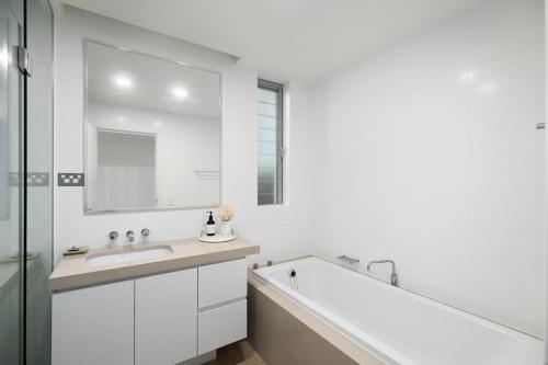 a white bathroom with a large tub and a sink at Beachfront Haven at Magenta in Magenta