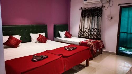 1 dormitorio con 2 camas con almohadas rojas y zapatos. en The Leisure Home Stay en Shādipur