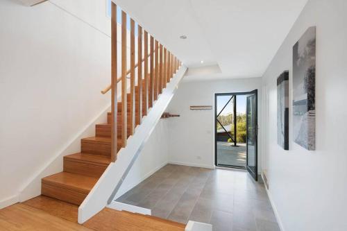 a staircase in a home with white walls and wooden floors at Beachwood - Pambula Beach in Pambula Beach