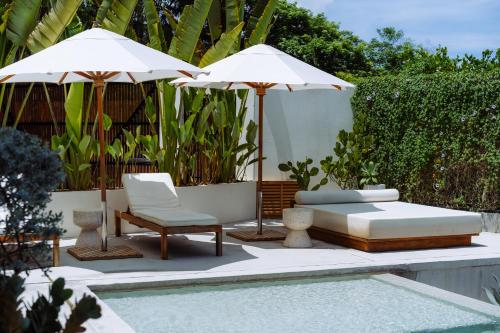 un patio con 2 sombrillas blancas, un sofá y sillas en Sky House Santa Teresa - Adults only, en Santa Teresa Beach