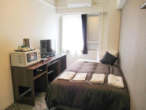 a hotel room with a bed and a television at HOTEL LiVEMAX BUDGET Kawasaki Ekimae in Kawasaki