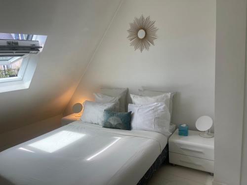 - un lit blanc avec des oreillers blancs et un miroir mural dans l'établissement La suite Monceau, à Paris