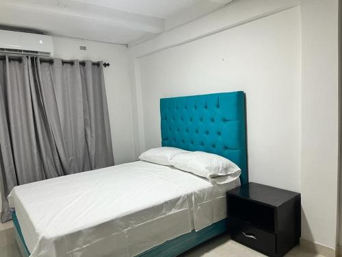 a bed with a blue headboard in a bedroom at hostal la niña carmen in Cartagena de Indias