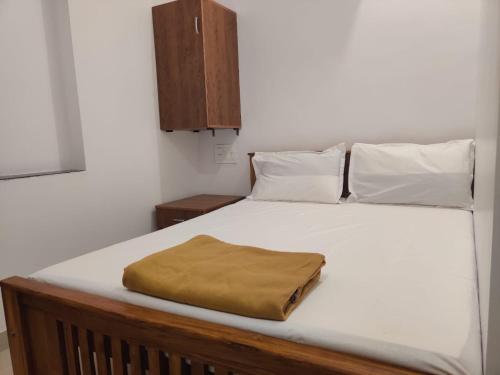 Elle comprend un grand lit blanc avec une couverture brune. dans l'établissement SRI BALAJI LODGING, à Tiruchchendūr