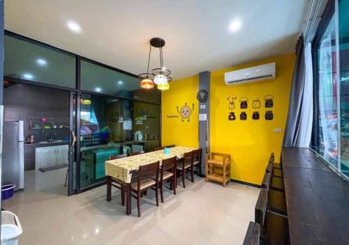 a dining room with yellow walls and a table and chairs at บ้านพักชะอำ Dream​ ​& Dear​ Fantasy​ Pool​ Villa​ Cha-am in Ban Sa