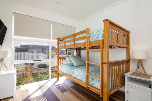 a bedroom with a bunk bed and a large window at LegaSea Lodge - Pet Friendly Beachfront with Plunge Pool in Shellharbour