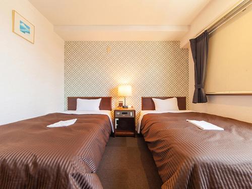 HOTEL LiVEMAX BUDGET Sagamihara في ساغاميهارا: غرفه فندقيه سريرين ومصباح