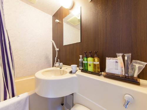 a bathroom with a sink and a toilet and a mirror at HOTEL LiVEMAX BUDGET Sagamihara in Sagamihara