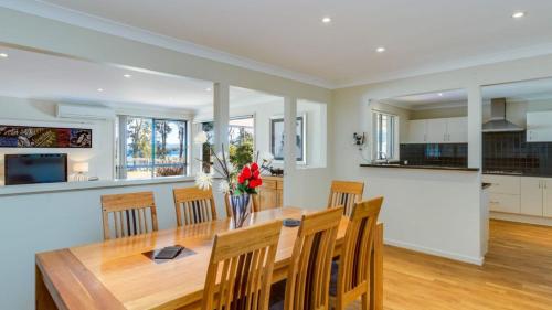 a kitchen and dining room with a wooden table and chairs at Peaceful Waterfront, wheelchair accessible - Stunning Location for Family Holiday in Sanctuary Point