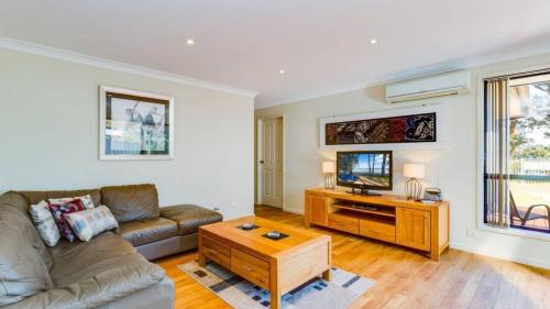 a living room with a couch and a tv at Peaceful Waterfront, wheelchair accessible - Stunning Location for Family Holiday in Sanctuary Point