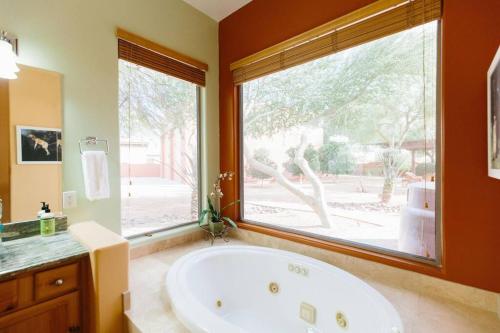 ein großes Bad mit einer Badewanne und einem großen Fenster in der Unterkunft Sprawling Arizona Oasis w/ Dream Backyard in Anthem