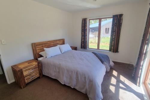 a bedroom with a large bed and a window at Sherwood Ranch Cottages - 403 Woodbank Road in Hanmer Springs