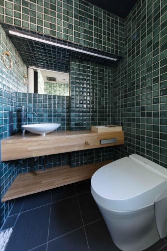 a green tiled bathroom with a toilet and a sink at 藤華/京都 in Kyoto
